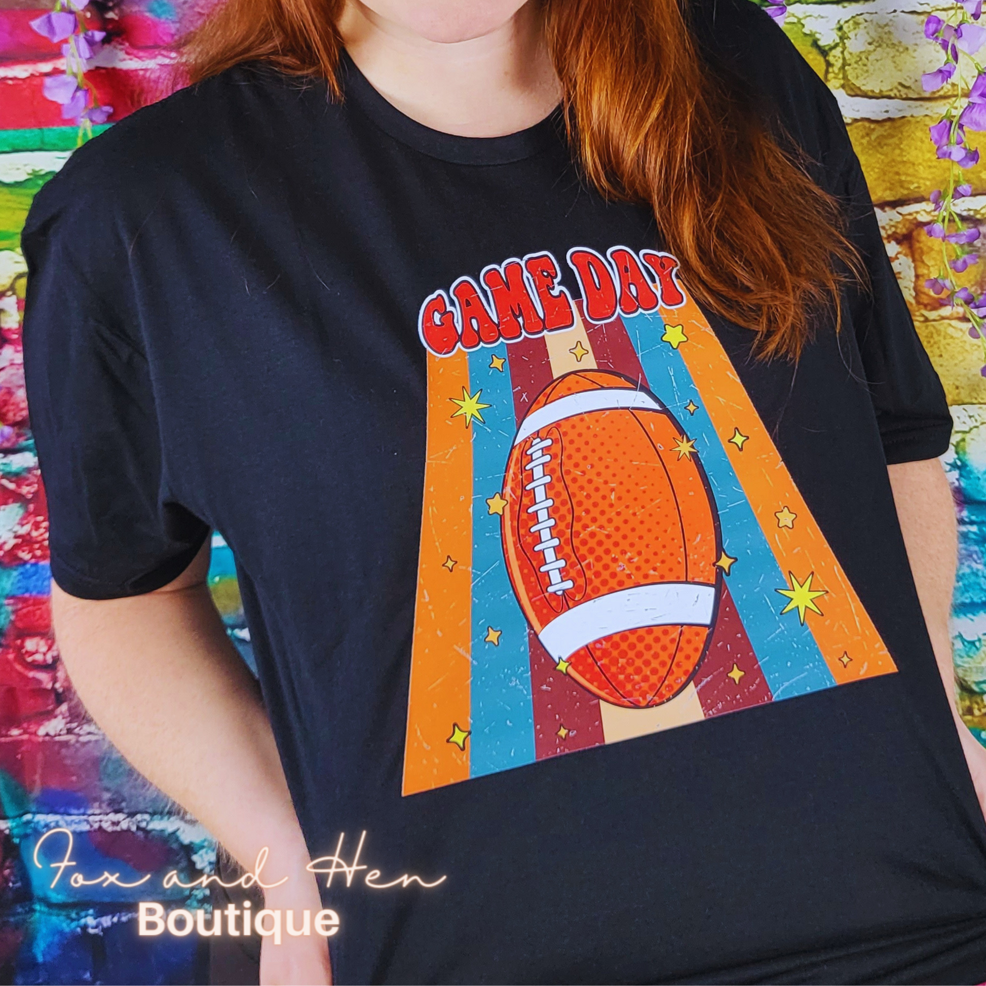 Game Day Football T-shirt. Black colored shirt. Displayed at an angle. Model is wearing a Large unisex fit.