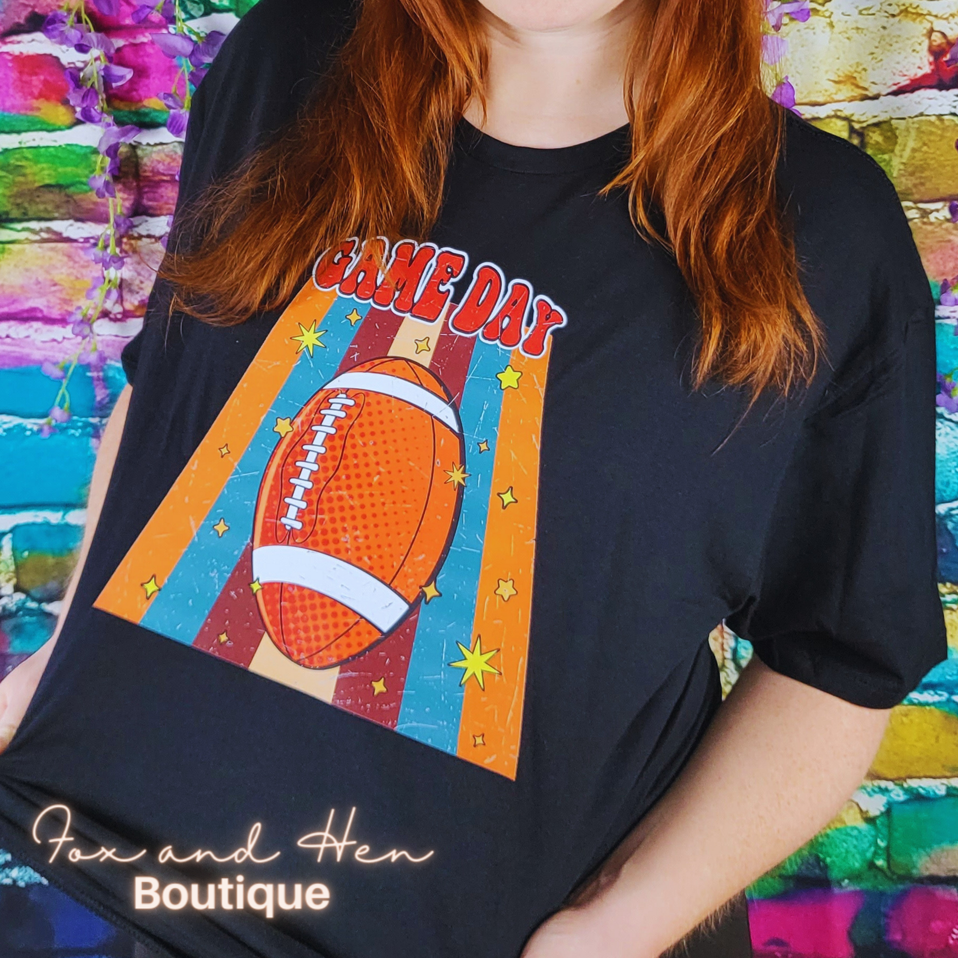 Game Day Football T-shirt. Black colored shirt. Displayed at an angle. Model is wearing a Large unisex fit.